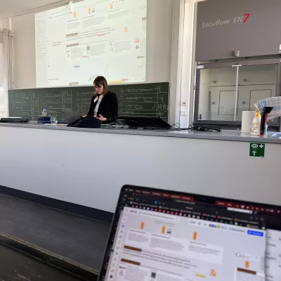 Bild aus einer Session, die eine Person zeigt. Im Hintergrund die Projektion zum Thema der Session: digitale Landschaft der Sammlungsdigitalisierung